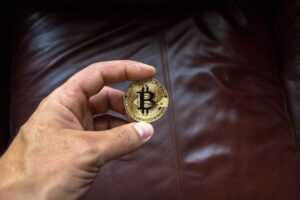 Persona che mantiene in mano un Bitcoin