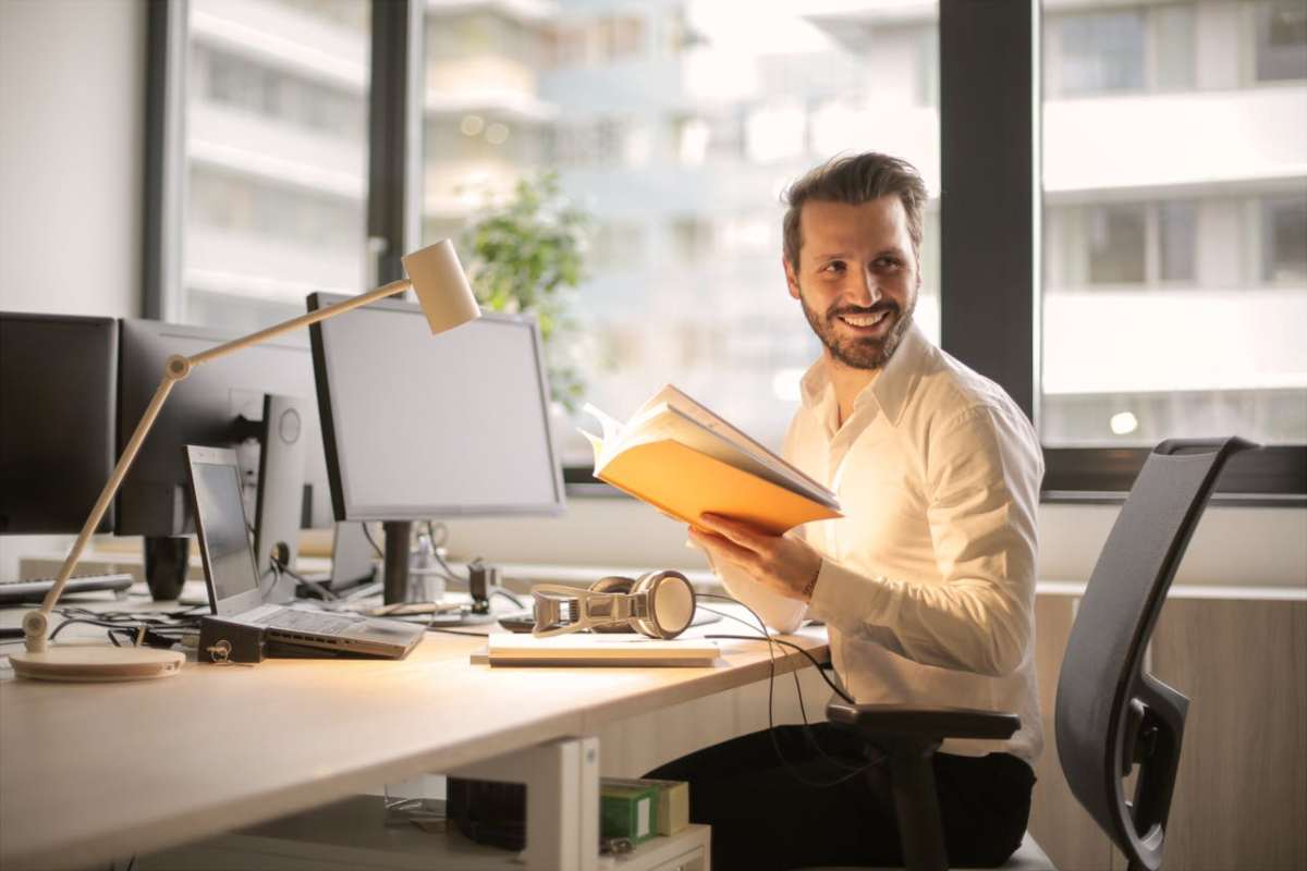 Persona che legge notizie su un libro e al computer