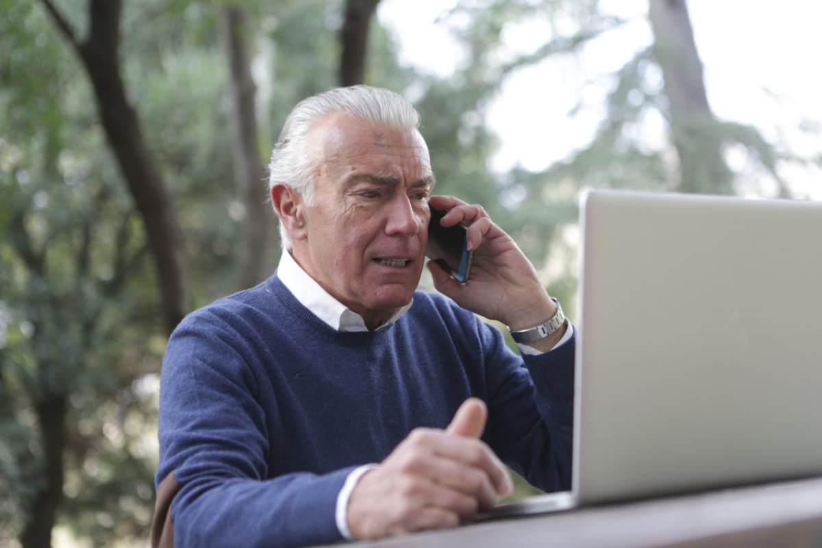 Pesrona che legge al computer mentre telefona