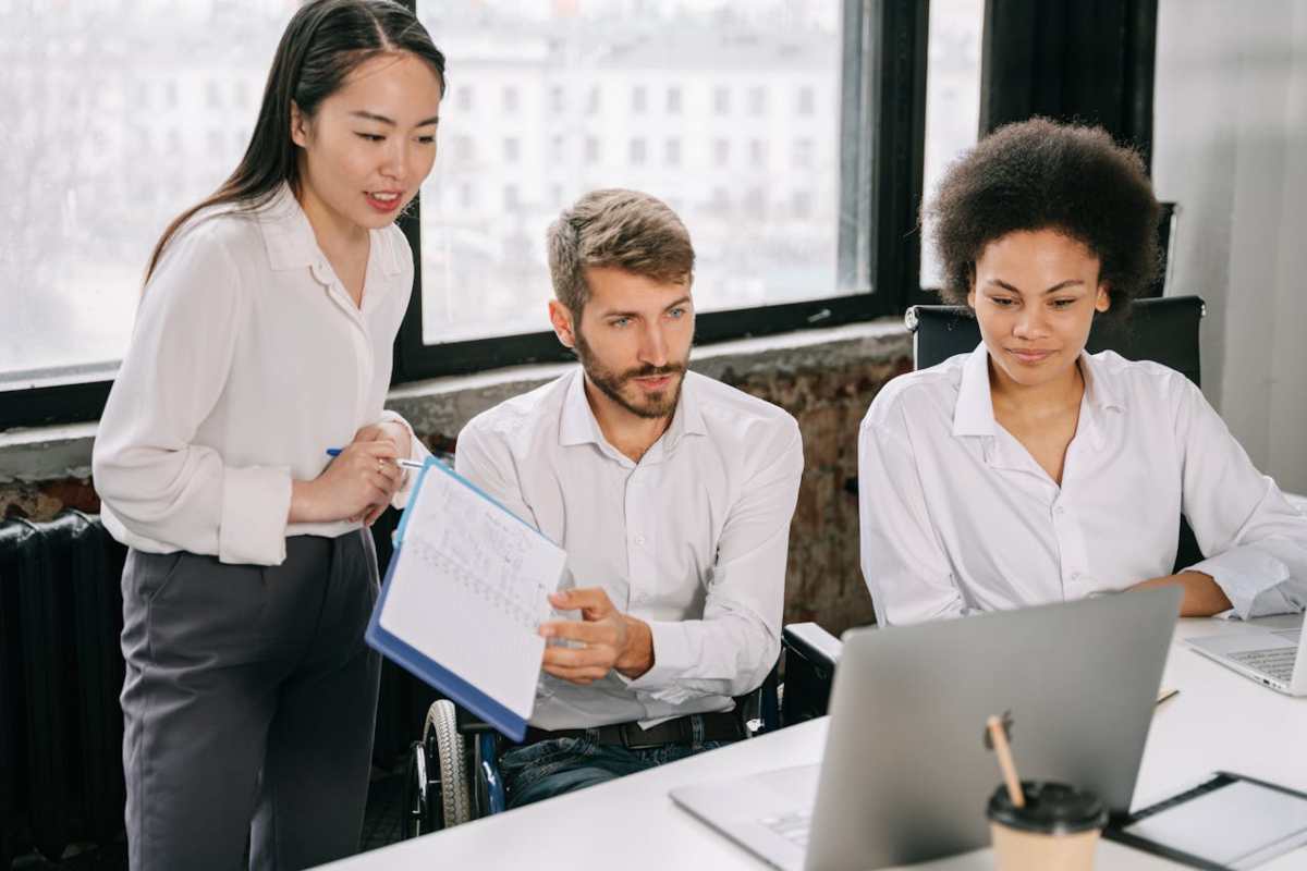 Disabile con colleghi al lavoro mentre leggono su un pc